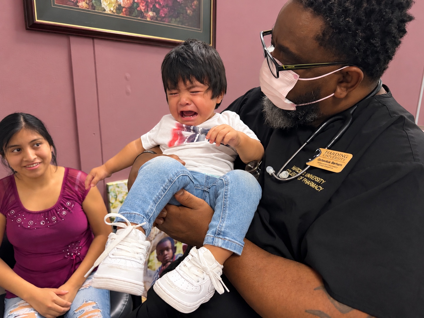 Un profesional sostiene a un niño acompañado de una niña